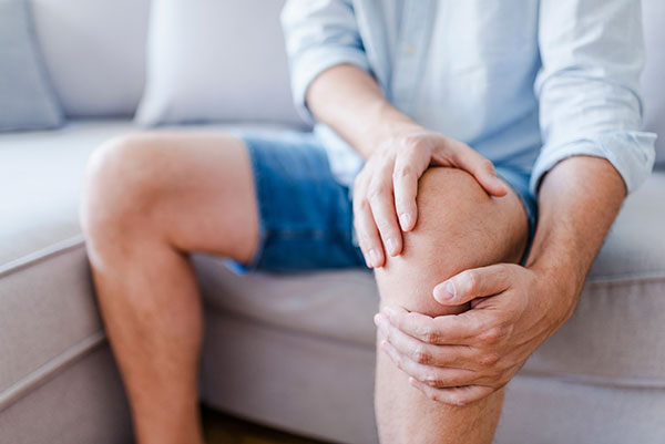 man gripping knee in pain due to arthritis